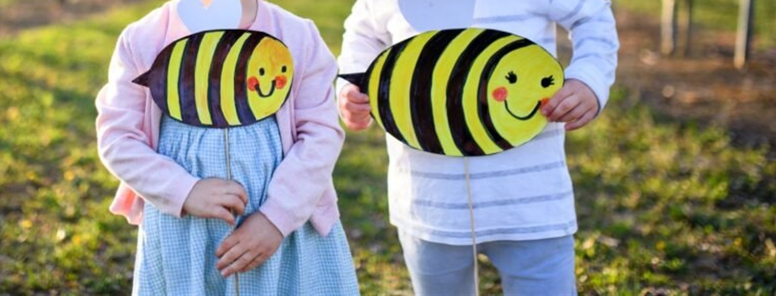 Niños en un campo en flor con abejas de papel pintadas por ellos, en un taller de Neurobee